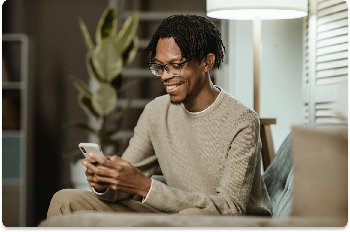Homem negro com moletom bege mexendo no celular